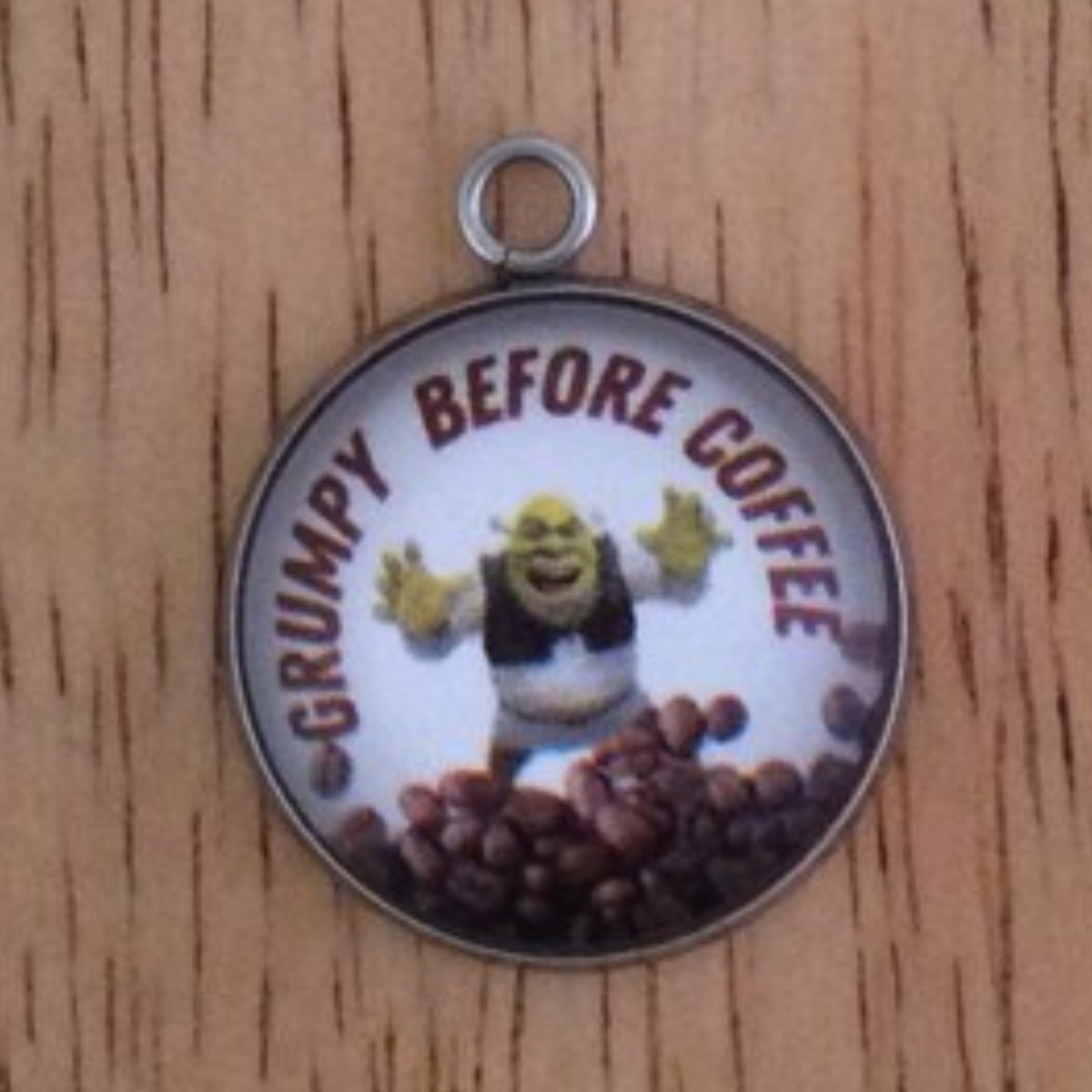 glass cabochon charm with a Shrek behind a pile of coffee beans and it says Grumpy Before Coffee