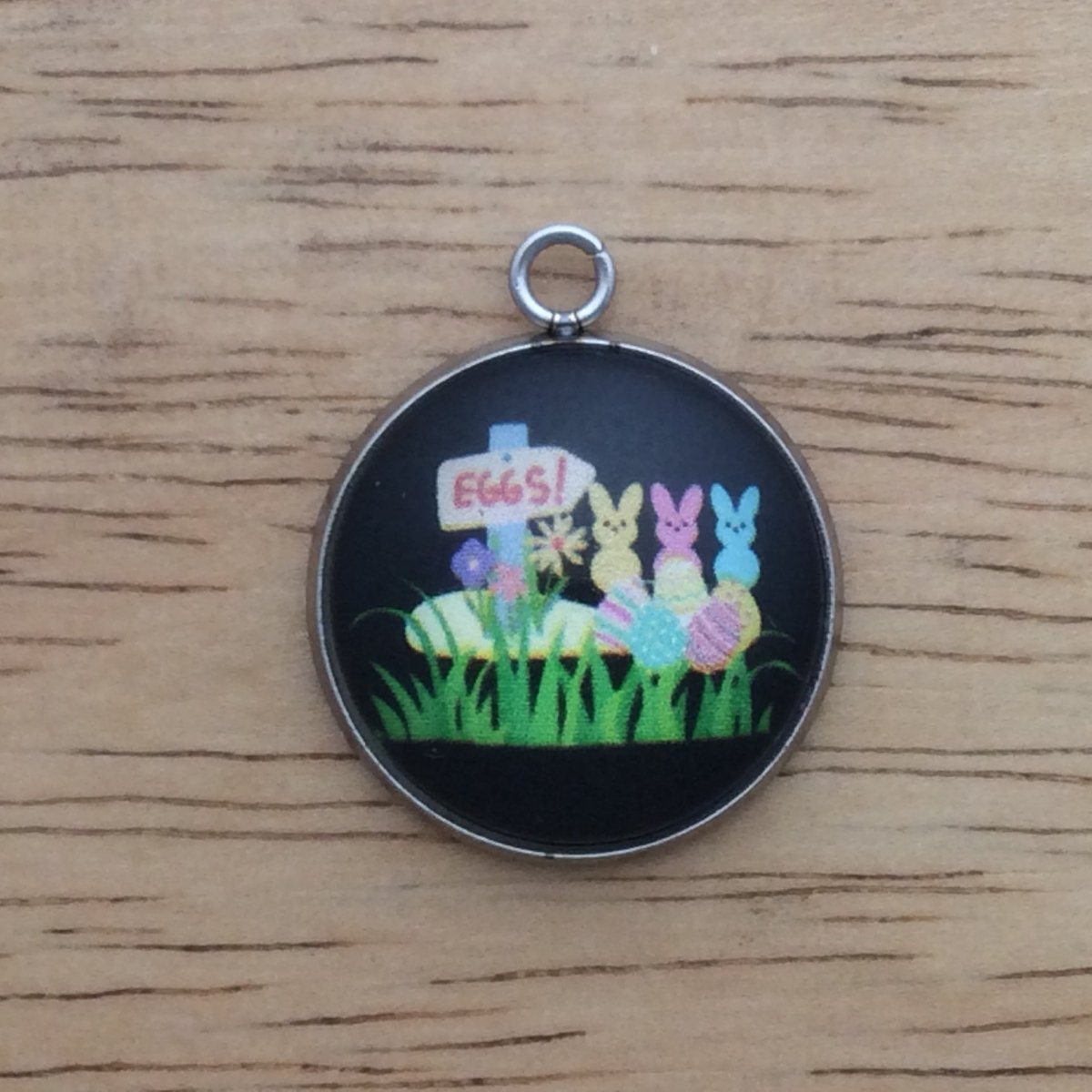 glass cabochon charm with a sign that says EGGS! with three peeps and easter eggs in the grass