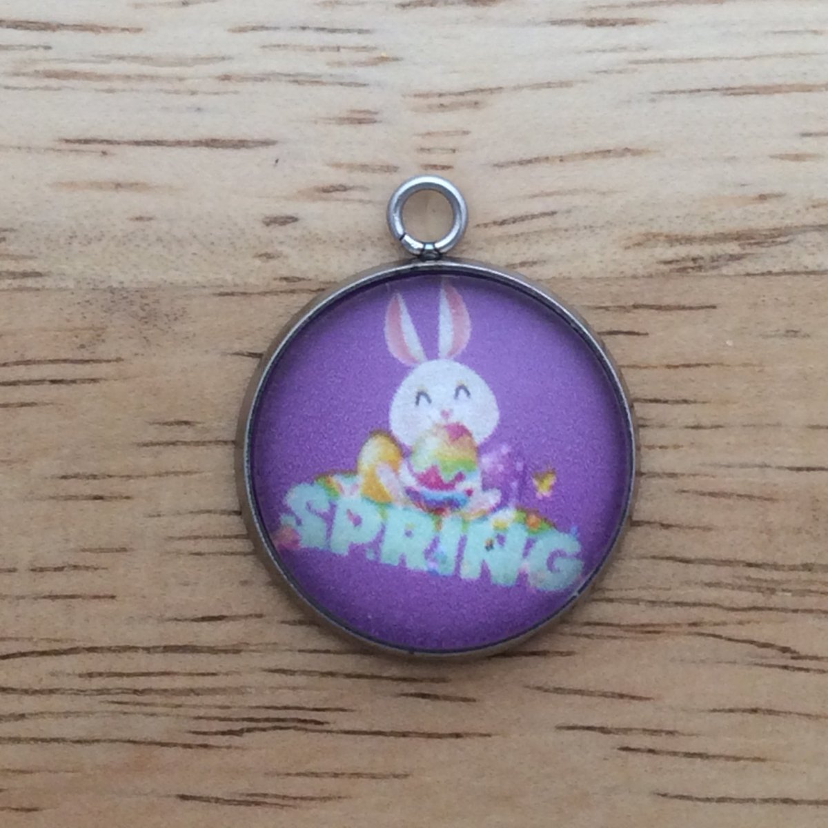 glass cabochon charm with a easter bunny with eggs above the word spring