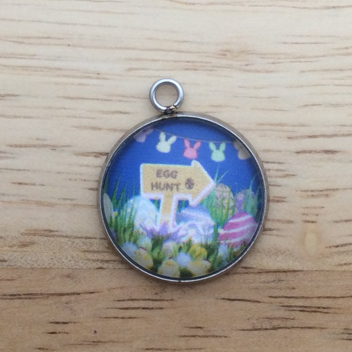 glass cabochon charm with a sign that says "Egg Hunt" surrounded by easter eggs in the grass