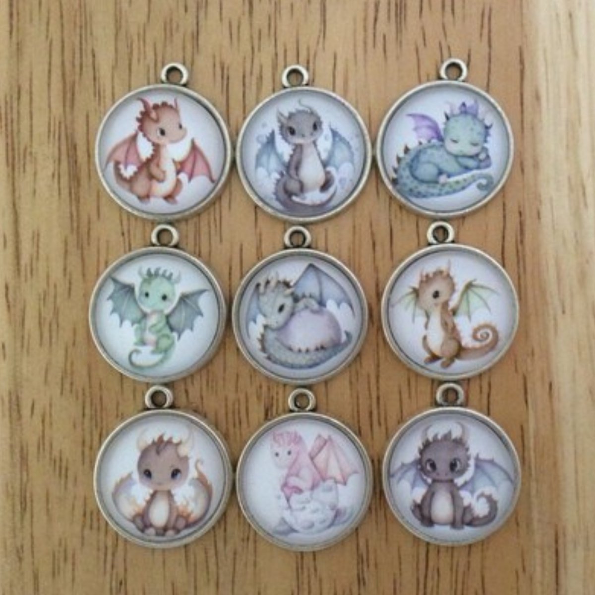 Set of 9 glass cabochon charms that show a variety of cute baby dragons