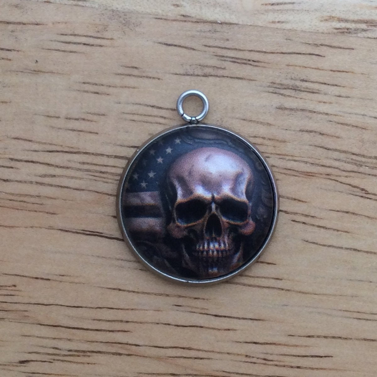 glass cabochon charm with a skull in front of American flag