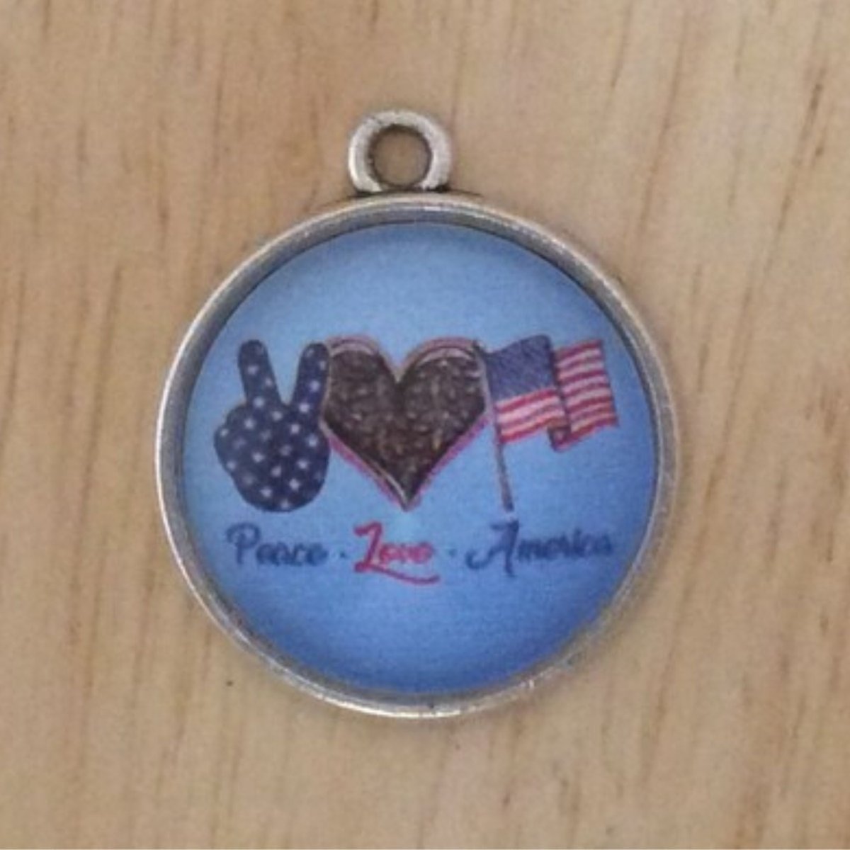 glass cabochon charm with a peace sign, heart, American flag and says peace-Love-America