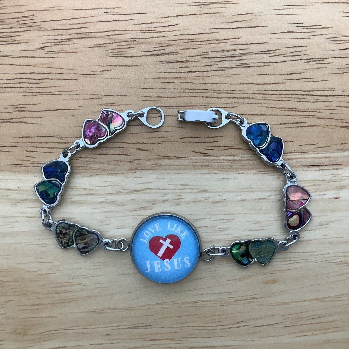 double paua heart charm bracelet with a glass cabochon charm stating 'Love like Jesus'as a centerpiece