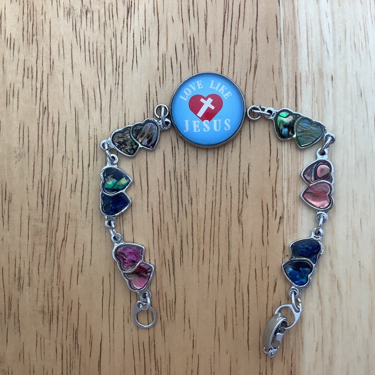 double paua heart charm bracelet with a glass cabochon charm stating 'Love like Jesus' as a centerpiece