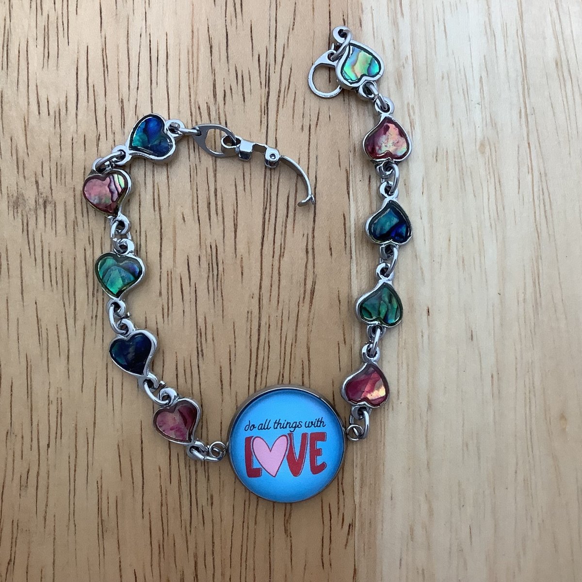 paua heart bracelet with the centerpiece charm stating 'do all things with love'