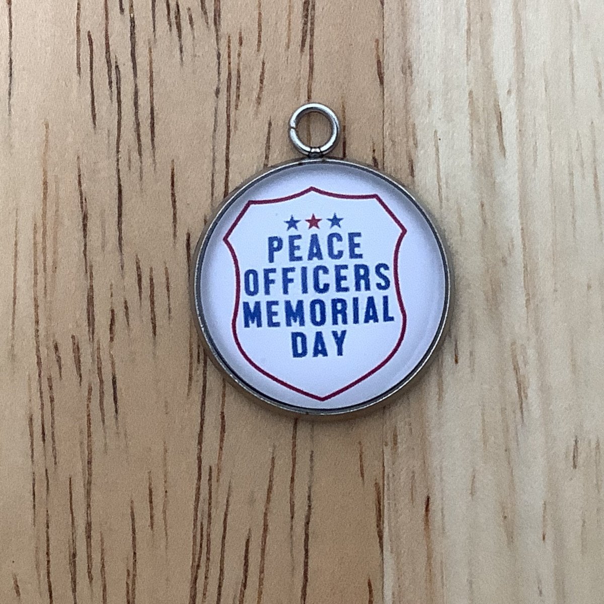 Charm featuring a police badge and the words 'peace officers memorial day' 