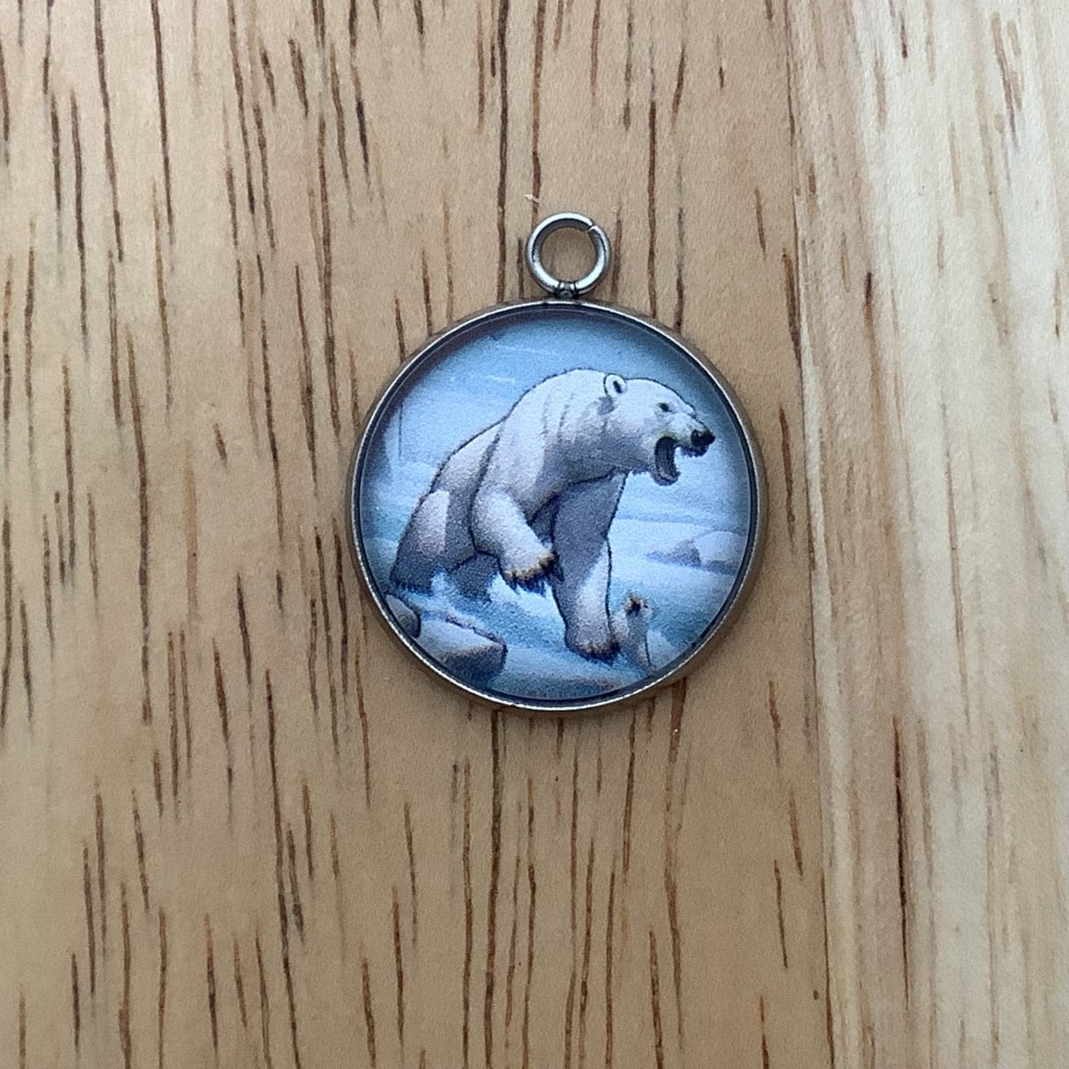 a charm of a very angry looking polar bear, he has a paw with claws up and barring his teeth