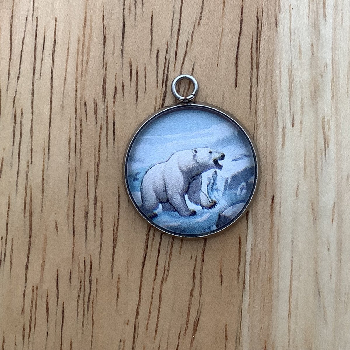 charm depicting a polar bear at the river with a fish falling out of his mouth