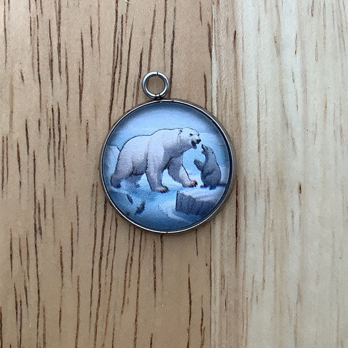 charm depicting a seal and a polar bear nose to nose and a fish jumping out of the river