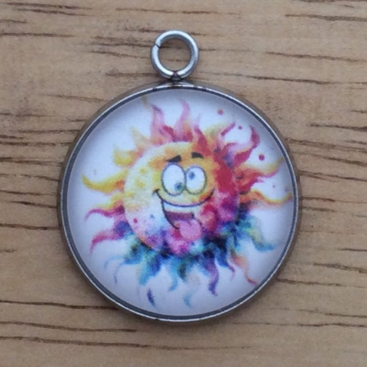 Glass cabochon charm with a funny faced, rainbow colored sun