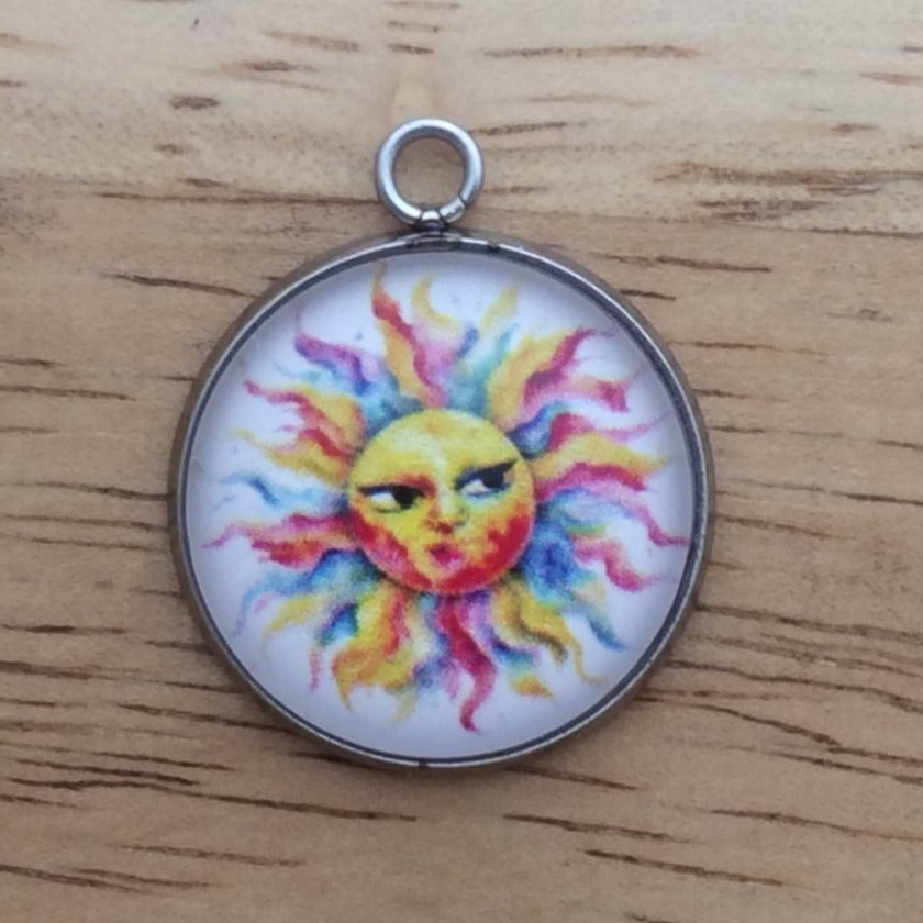 Glass cabochon charm with a funny faced, rainbow colored sun