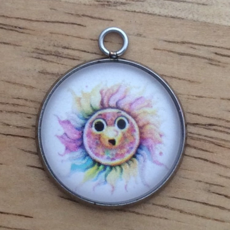 Glass cabochon charm with a funny faced, rainbow colored sun