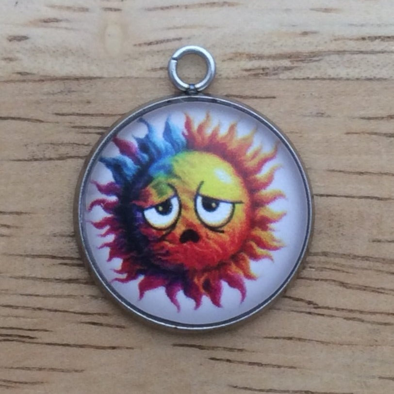 Glass cabochon charm with a funny faced, rainbow colored sun