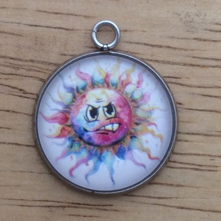 Glass cabochon charm with a funny faced, rainbow colored sun