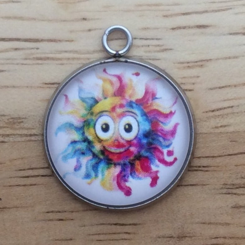 Glass cabochon charm with a funny faced, rainbow colored sun