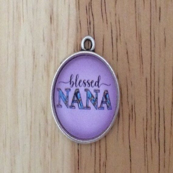 Glass cabochon charm that says blessed nana on a purple background