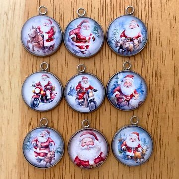 9 glass cabochon charms with images of santa playing in the snow