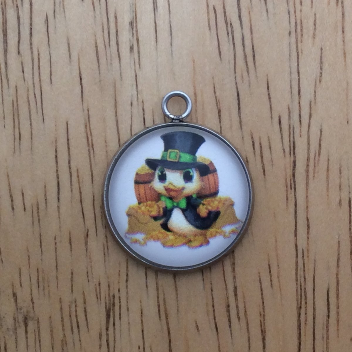 glass cabochon charm with a duck in st Patricks clothing in front of 2 barrels and 2 bags of gold