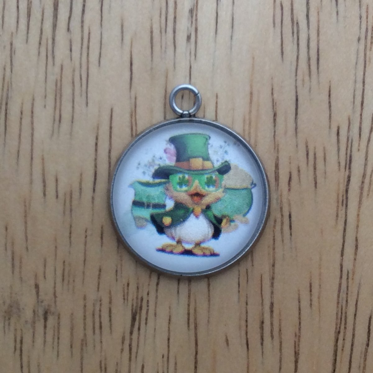 glass cabochon charm with a duck in st Patricks clothing in front of a leprechaun boot and a pot of gold