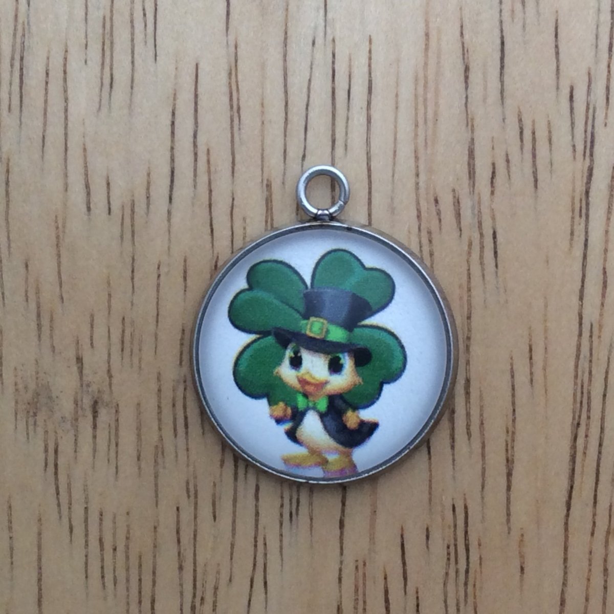 glass cabochon charm with a duck in st Patricks clothing in front of a shamrock