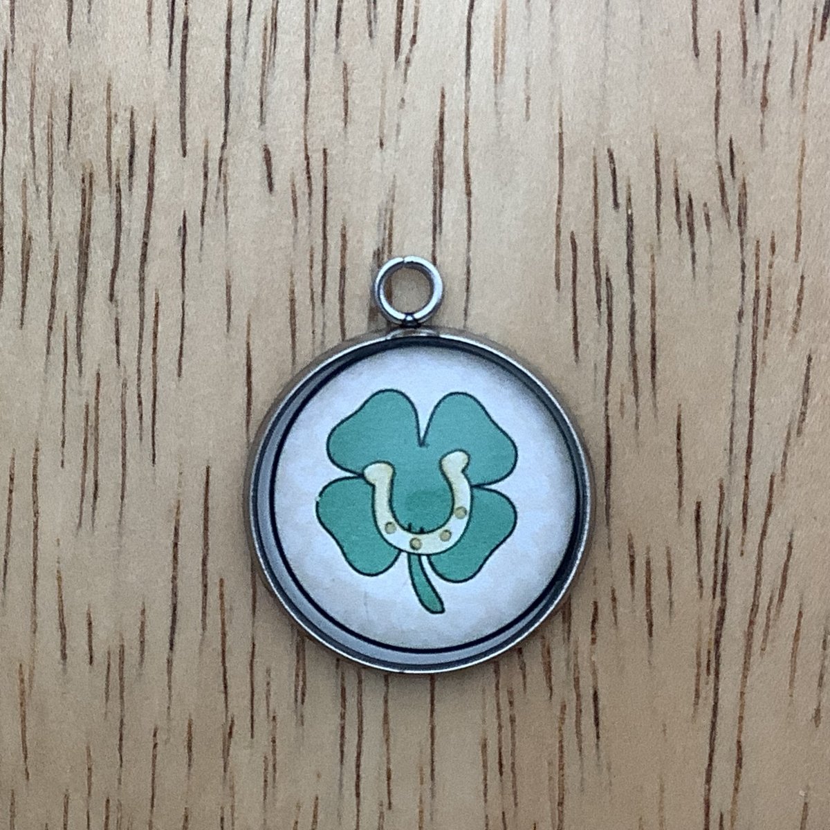 Charm with a 4 leaf clover and a horseshoe in the middle of it