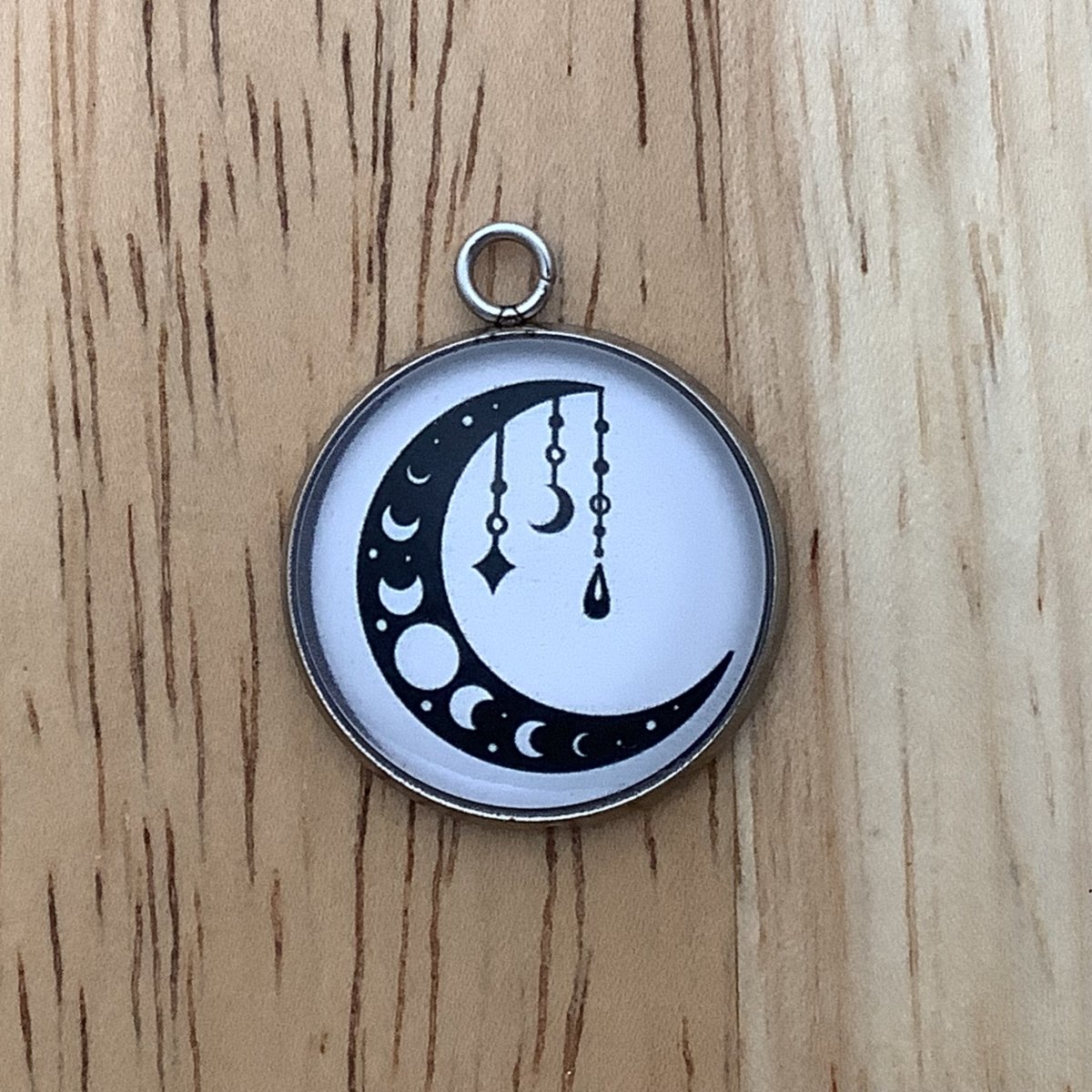 Charm featuring moon sliver with moon phases it it with crystals 