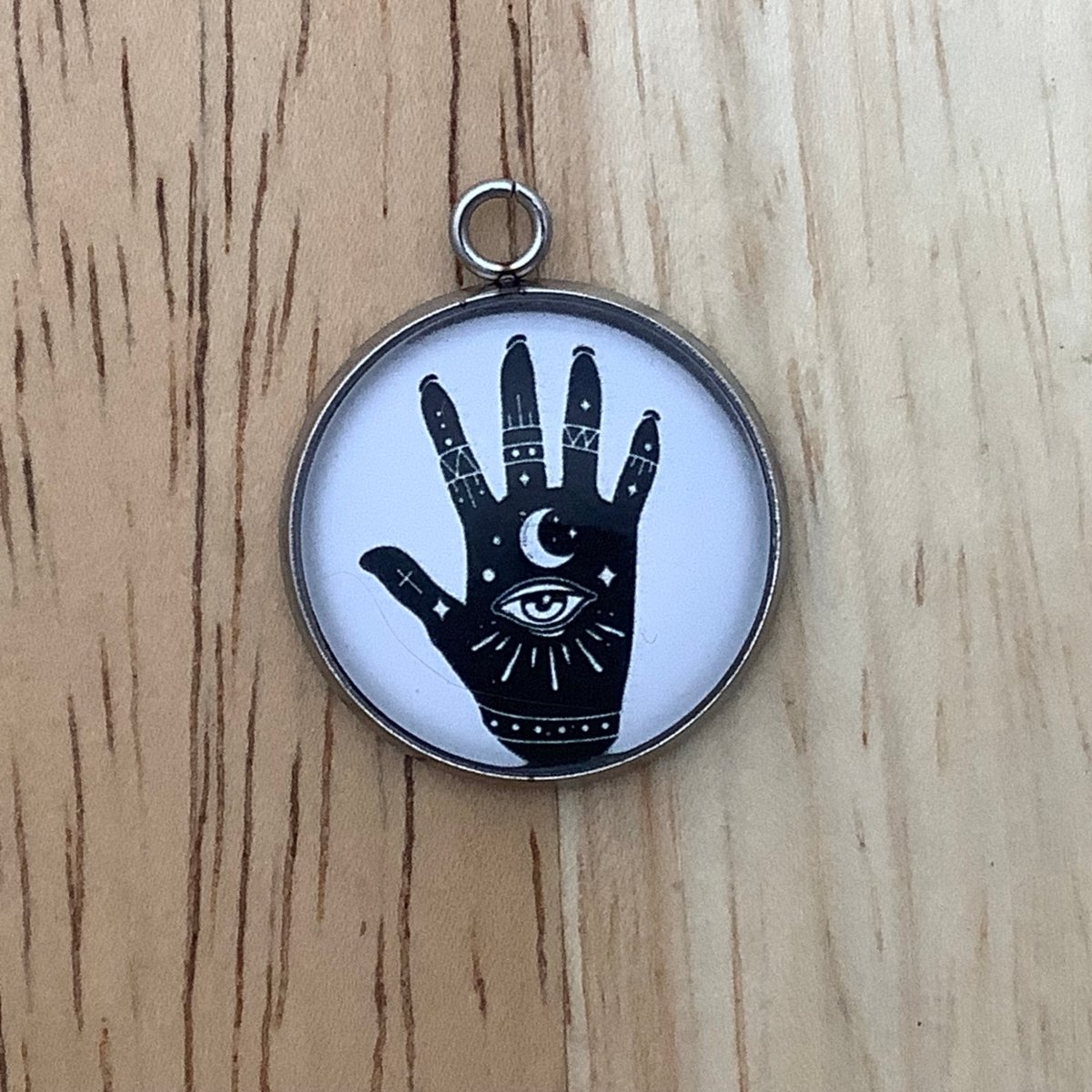 Charm featuring a black palm with an eye and palm reading symbols