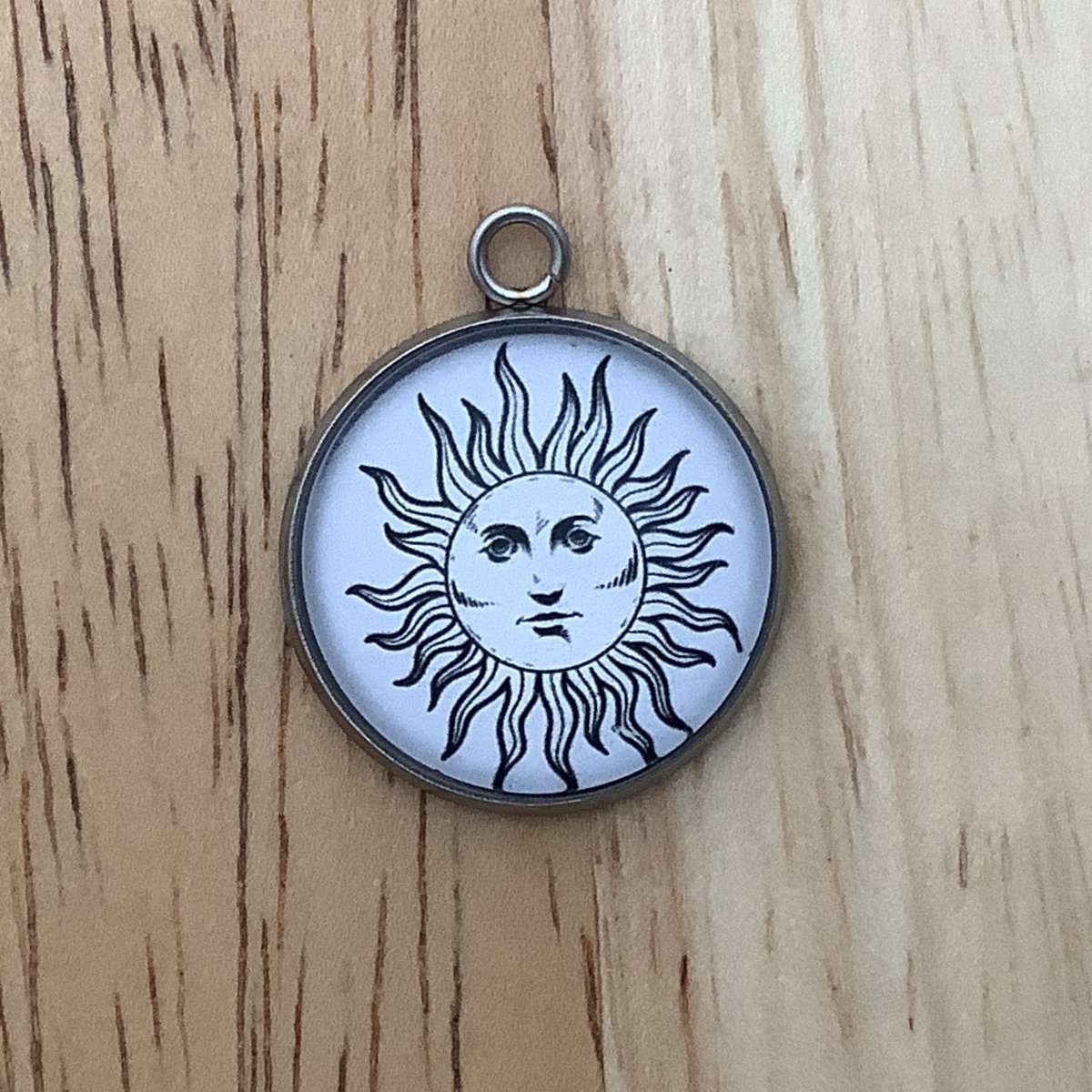 Charm featuring a sun with a face