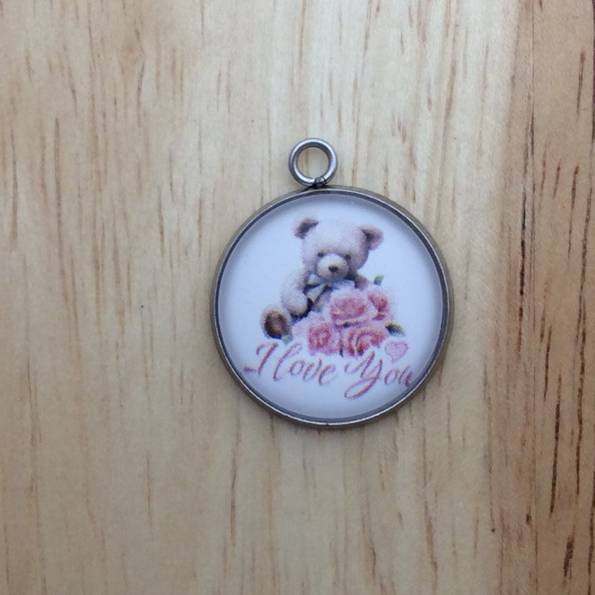 one glass cabochon charm with a teddy bear holding three pink roses and it says I Love You