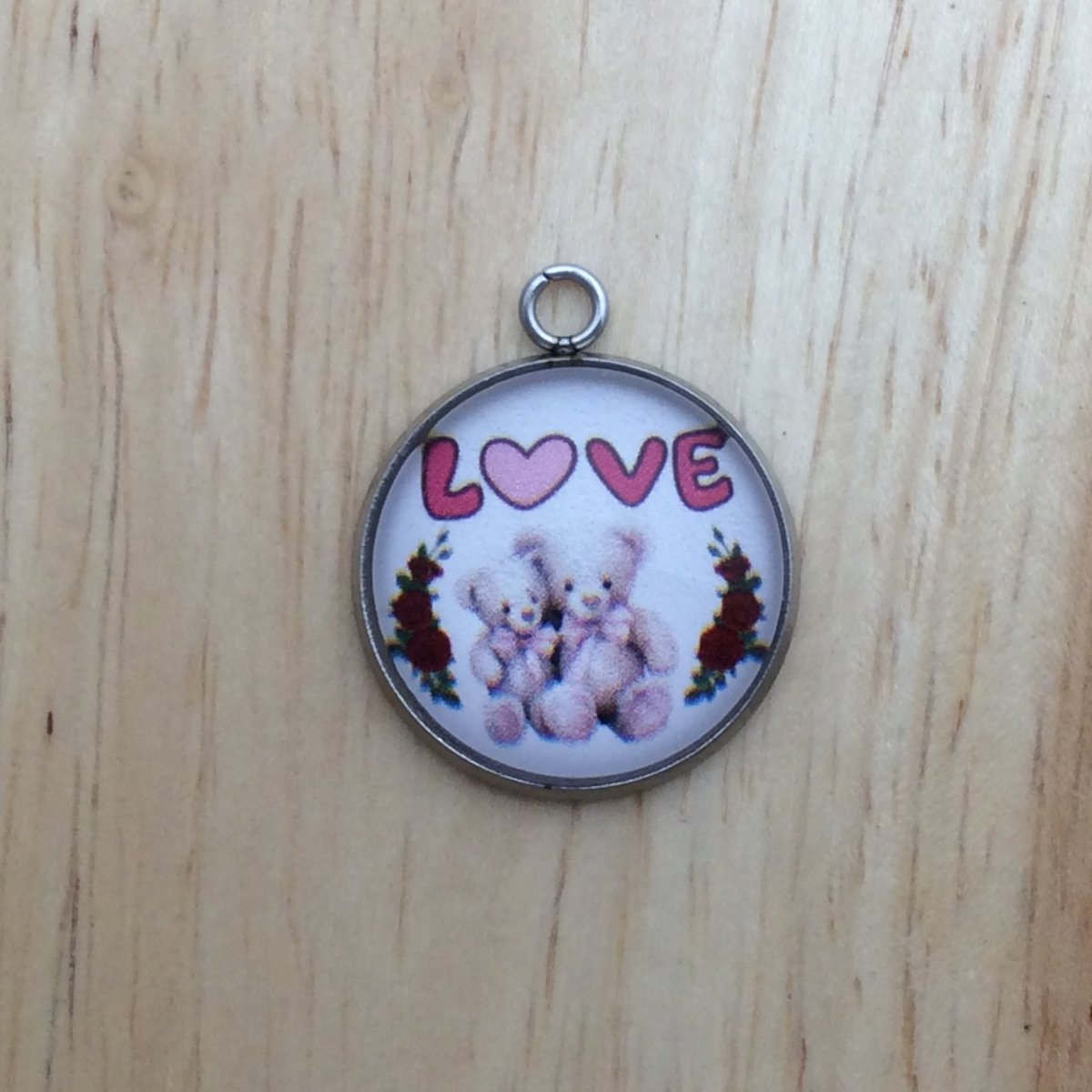 one glass cabochon charm with two sitting teddy bears between two rose vines with the word LOVE 