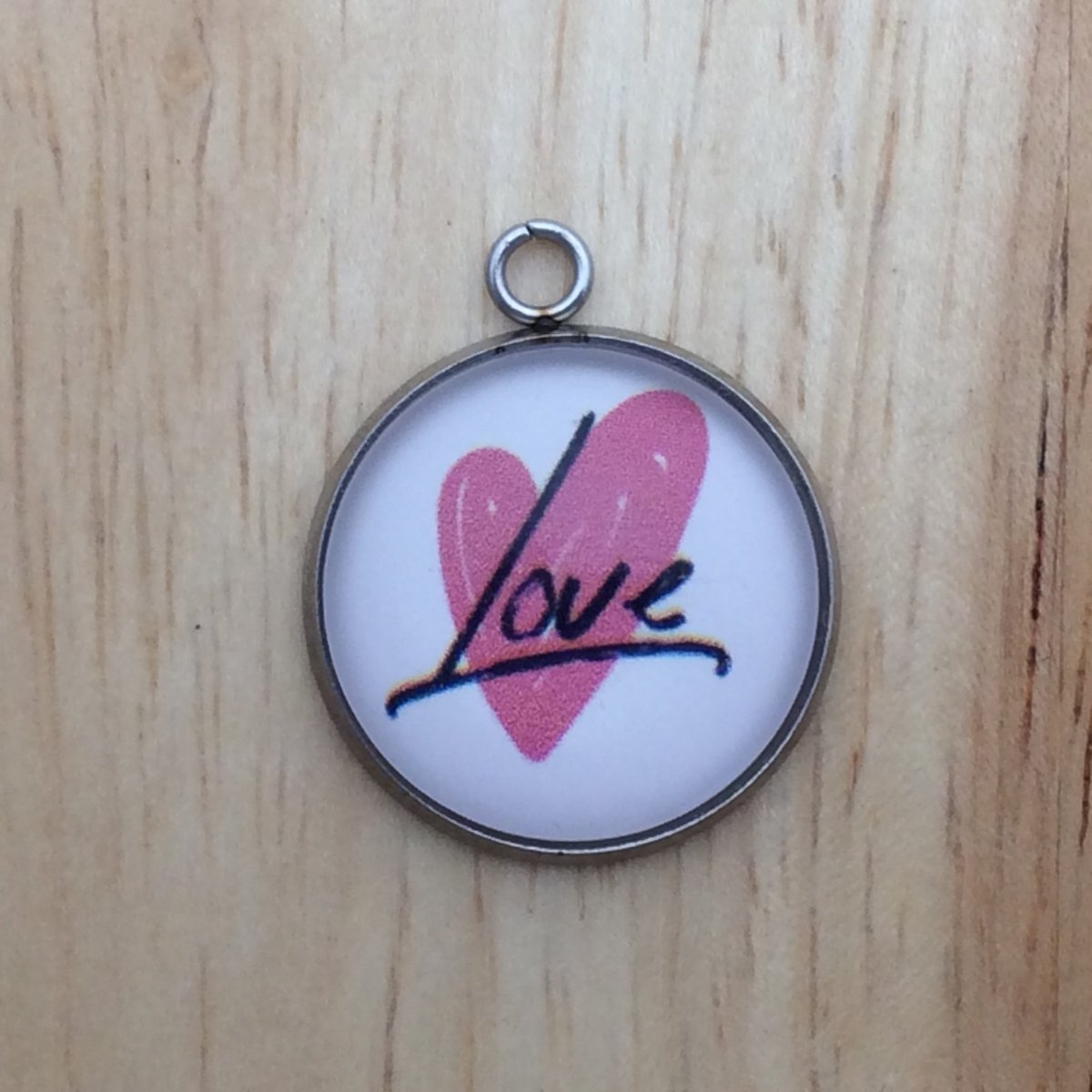 one glass cabochon charm with a pink heart that says love