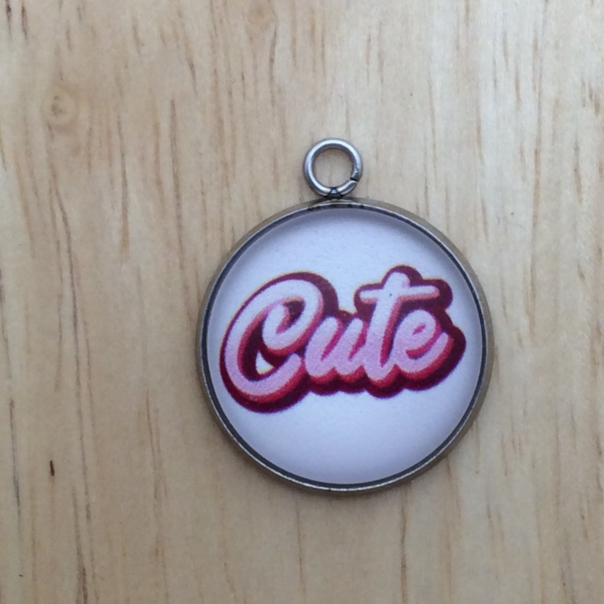 one glass cabochon charm with the word Cute in pink