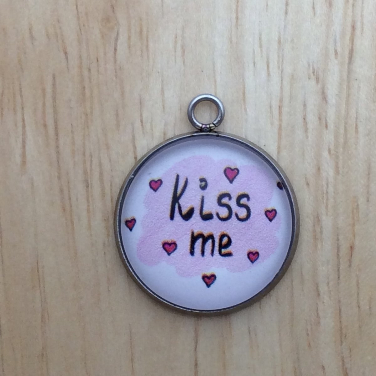 one glass cabochon charm with pink brushy strokes, red hearts and says kiss me